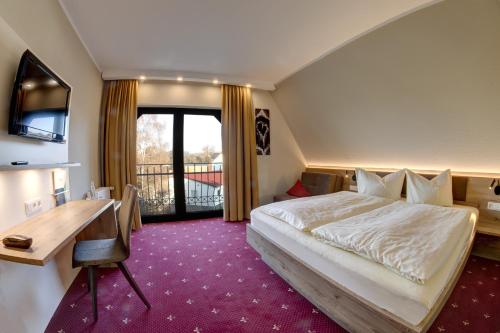 a hotel room with a bed and a desk and a balcony at Hotel Zur Schmiede in Alsfeld