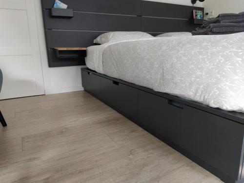 a bedroom with a black bed frame and a wooden floor at De Kuiperij in Arcen