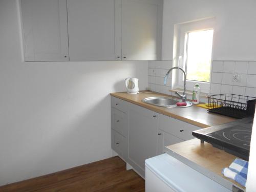 eine Küche mit weißen Schränken, einem Waschbecken und einem Fenster in der Unterkunft Gosciniec in Kodeń