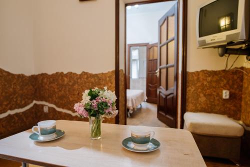 a table with two cups and a vase of flowers at Villa Viktoriya Hotel in Truskavets