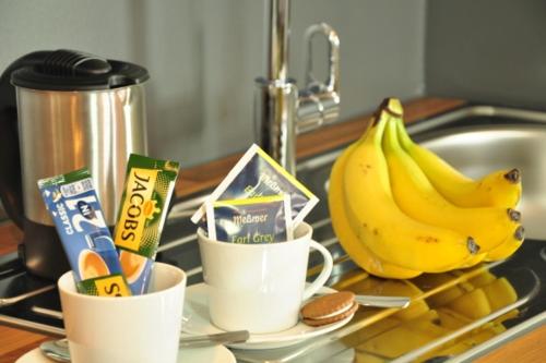 a kitchen counter with two cups of coffee and bananas at Motel am Fürfelder Schloss in Bad Rappenau
