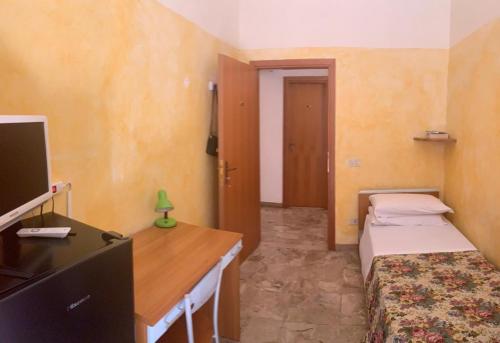 a room with two beds and a desk and a television at HostelCiompi in Siena