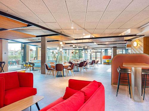 a lobby with a red couch and tables and chairs at Ibis Styles Madrid City Las Ventas in Madrid