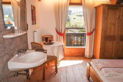 een badkamer met een wastafel, een bed en een raam bij Rosas Ferienwohnung in Fieberbrunn