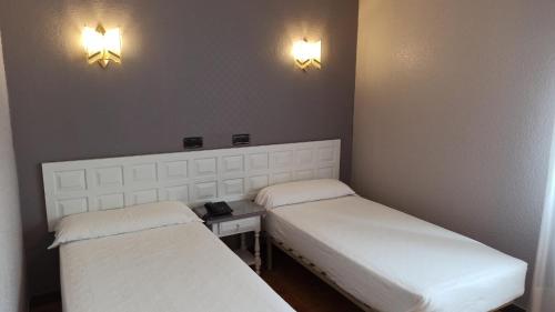 two beds in a small room with lights on the wall at Hotel Las Vegas in Burgos