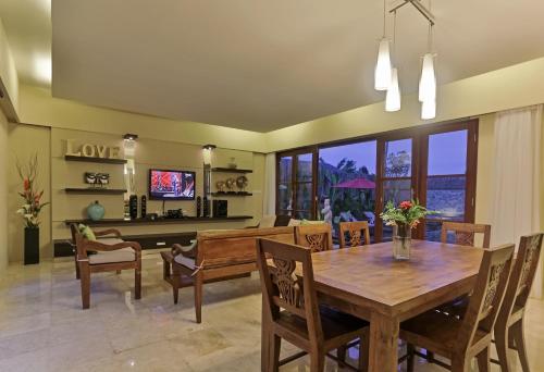 a dining room with a wooden table and chairs at Villa Kumuda by Nakula in Canggu