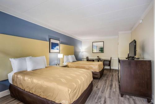 a hotel room with two beds and a flat screen tv at Quality Inn Hampton - Newport News in Hampton