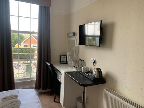 a hotel room with a desk with a television on the wall at The Lawns Guest House in Retford