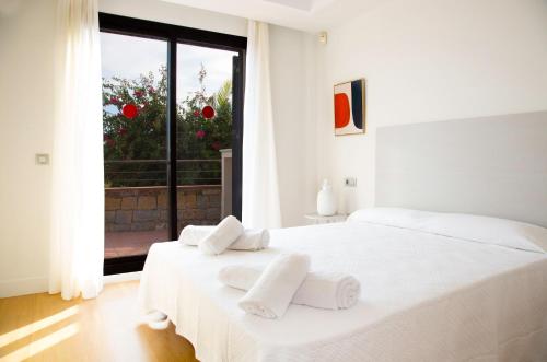 a white bedroom with two beds and a window at Casas del Mar Boutique in Casares