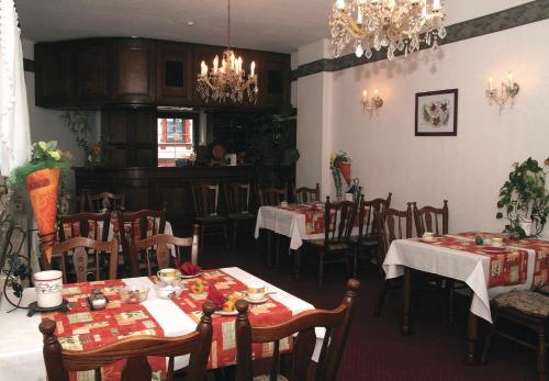 a dining room with tables and chairs and a chandelier at Hotel Jägerhalle in Falkenstein
