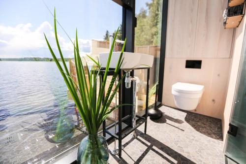 een badkamer met een toilet en een vaas met een plant bij Lake Hotel Lehmonkärki - Haasi Mirror Houses in Asikkala