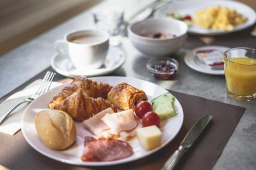 a table with a plate of food and a cup of coffee at Tailormade Hotel STANS SÜD in Stans