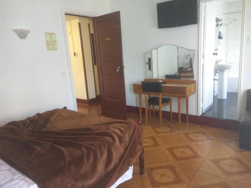 a bedroom with a bed and a desk and a mirror at Hotel Paulista in Porto