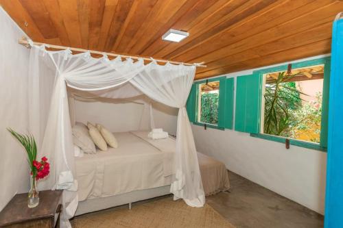 1 dormitorio con 1 cama con dosel y 2 ventanas en Casa do Pescador, en Praia do Espelho