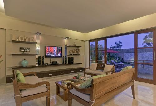 a living room with a couch and a tv at Villa Kumuda by Nakula in Canggu