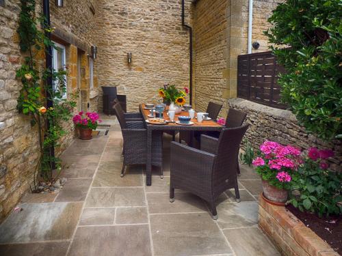a table and chairs on a patio with flowers at Rathbone Cottage in Stow on the Wold