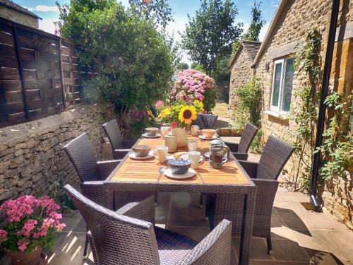 a wooden table and chairs on a patio at Rathbone Cottage in Stow on the Wold