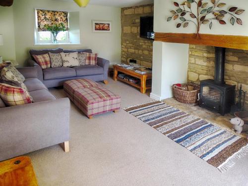 a living room with a couch and a fireplace at Greystones Cottage in Bourton on the Water