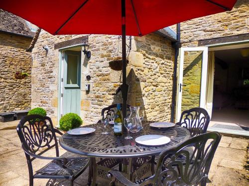 a table with a red umbrella on a patio at Greystones Cottage in Bourton on the Water