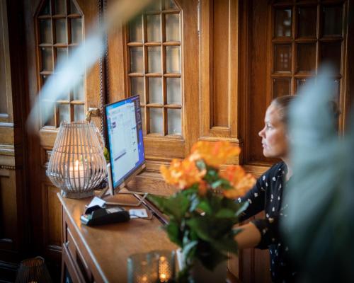 a woman sitting at a desk with a computer at Stadshotellet Kristianstad in Kristianstad
