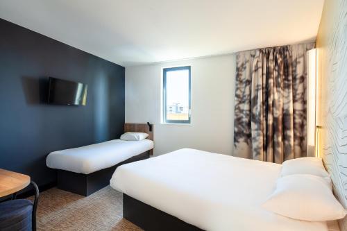a hotel room with two beds and a tv at B&B HOTEL Paris Porte de Bagnolet in Bagnolet