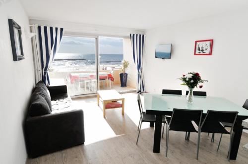 Sala de estar con mesa y vistas al océano en Appartement Estaque, en Valras-Plage