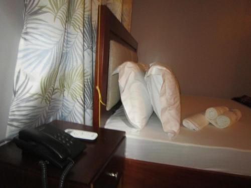 Habitación de hotel con cama con almohadas y teléfono en Jakicha Motel, en Dar es Salaam
