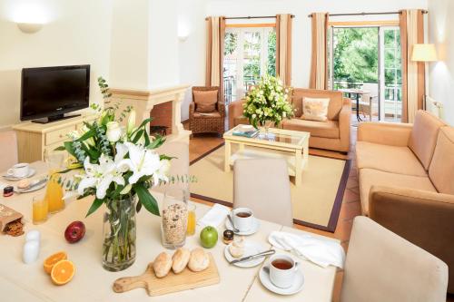 a living room with a table with a vase of flowers at The Village – Praia D’El Rey Golf & Beach Resort in Casal da Lagoa Seca
