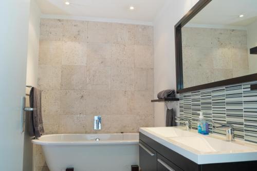 ein Badezimmer mit einer Badewanne, einem Waschbecken und einem Spiegel in der Unterkunft The Nicol Hotel Bedfordview in Johannesburg