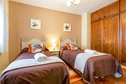 a bedroom with two beds and a wooden cabinet at Alojamiento Los Pradillos in Capileira