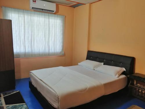 um quarto com uma grande cama branca e uma janela em KLUANG BARAT HOMESTAY em Keluang