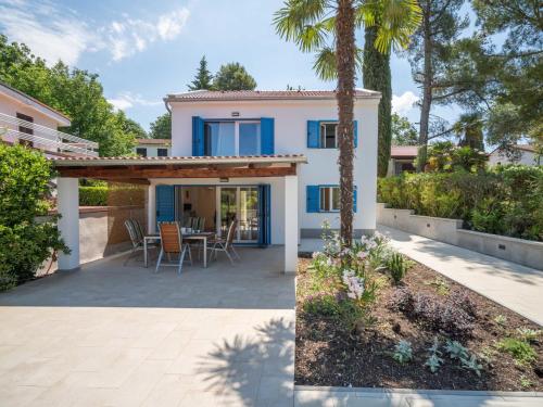 a home with a patio and a house with a palm tree at Holiday Home Natali by Interhome in Njivice