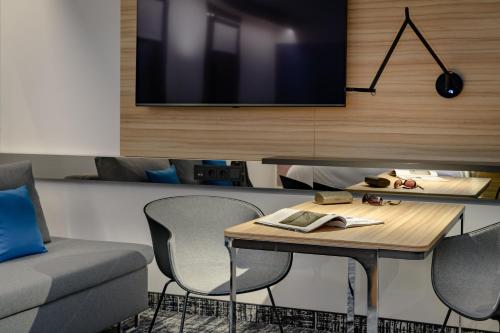 a living room with a table and chairs and a tv at Novotel Suites Berlin City Potsdamer Platz in Berlin
