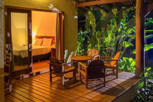 a wooden deck with a table and chairs and a bed at Charm Bahia Residencias in Arraial d'Ajuda