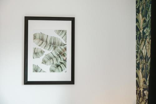 a framed picture of a plant on a white wall at North-Hotel in Hamburg
