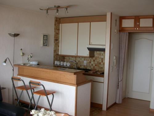 a kitchen with a counter and two chairs in it at Studio Zeezicht De Sloep Koksijde in Koksijde