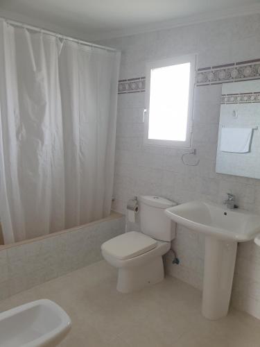 a white bathroom with a toilet and a sink at Alojamiento Café Soles in Denia