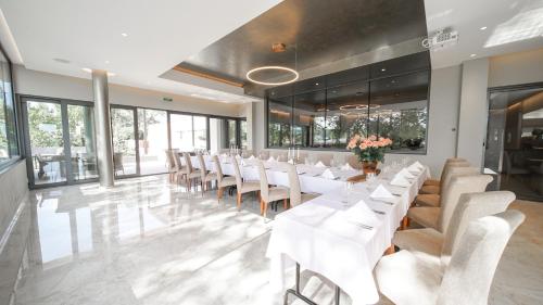 a dining room with white tables and chairs and windows at MÁJ Hotel Medical Wellness in Piešťany