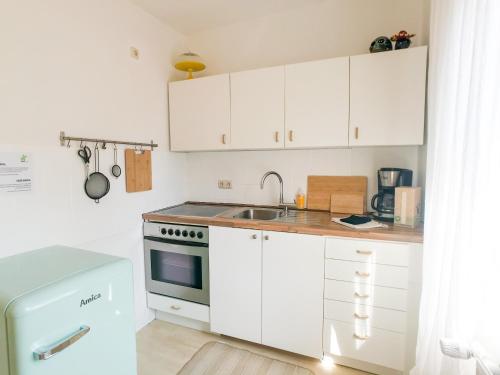 una pequeña cocina con armarios blancos y fregadero en Dream Green Apartment 'Frida' en Gladenbach