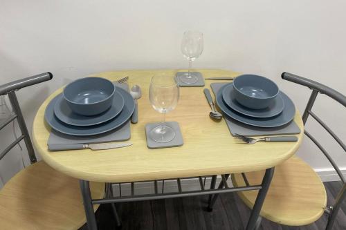 una mesa de madera con platos y copas de vino. en Stadium Nook, en Wembley