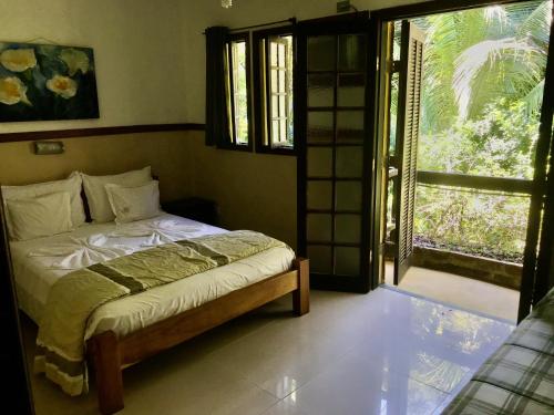 a bedroom with a bed and a sliding glass door at Hotel Pousada Katmandu in Maresias