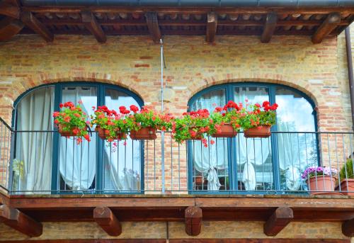 three windows with red flowers on a balcony at Da Fabiana in Bossolasco