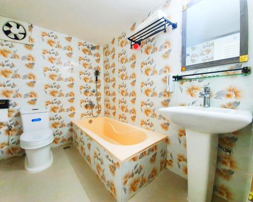 ein Bad mit einem Waschbecken und einem WC in der Unterkunft Hotel Khan Palace in Kuakata