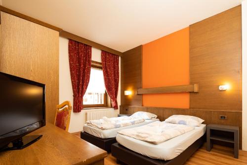 Residence San Marco by Alpenwhite في ليفينو: غرفة فندقية بسريرين وتلفزيون بشاشة مسطحة