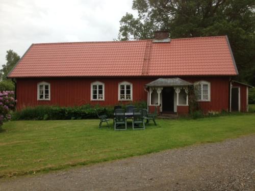 a red house with a table and chairs in front of it at Charmig hallandslänga nära Ullared in Ullared