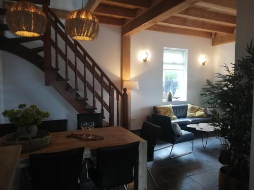a living room with a table and chairs and a staircase at Vakantiehuis Idylle aan Zee, privé SAUNA in Sint Maartensvlotbrug