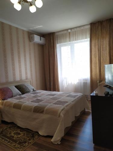 een slaapkamer met een groot bed en een raam bij Элегантная двухкомнатная квартира в центре in Novorossiejsk