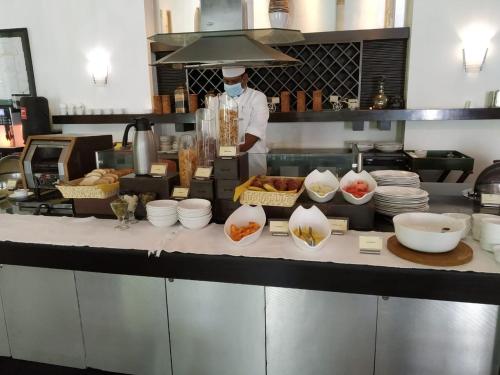 a chef in a kitchen preparing food in a kitchen at The Palms Town & Country Club - Resort in Gurgaon