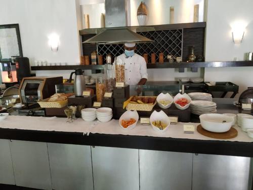 a chef is standing in a kitchen preparing food at The Palms Town & Country Club - Resort in Gurgaon