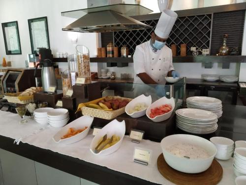 a chef in a kitchen preparing food in bowls at The Palms Town & Country Club - Resort in Gurgaon